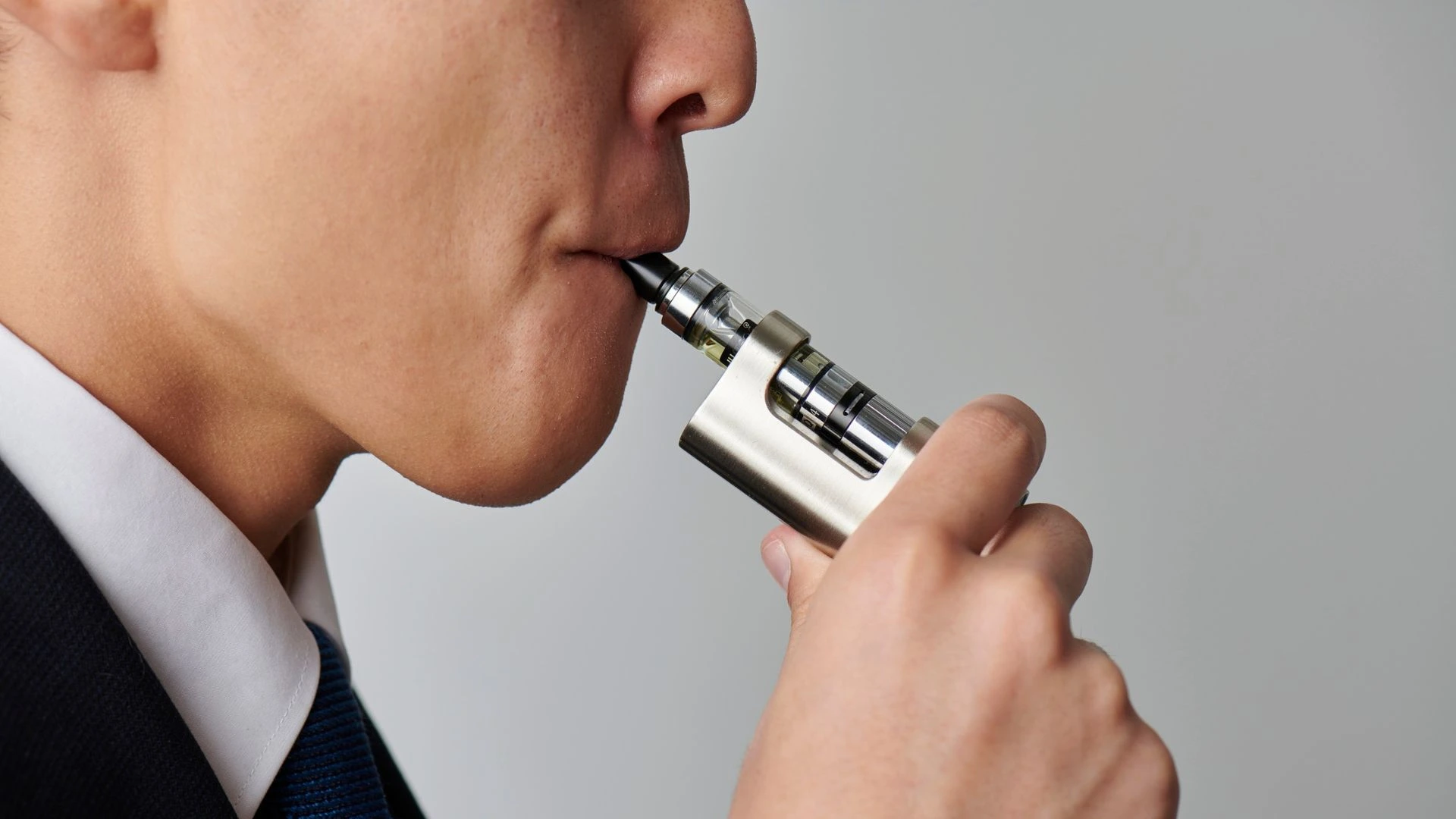 Close-up of a person using a modern vape device, inhaling vapor from an electronic cigarette