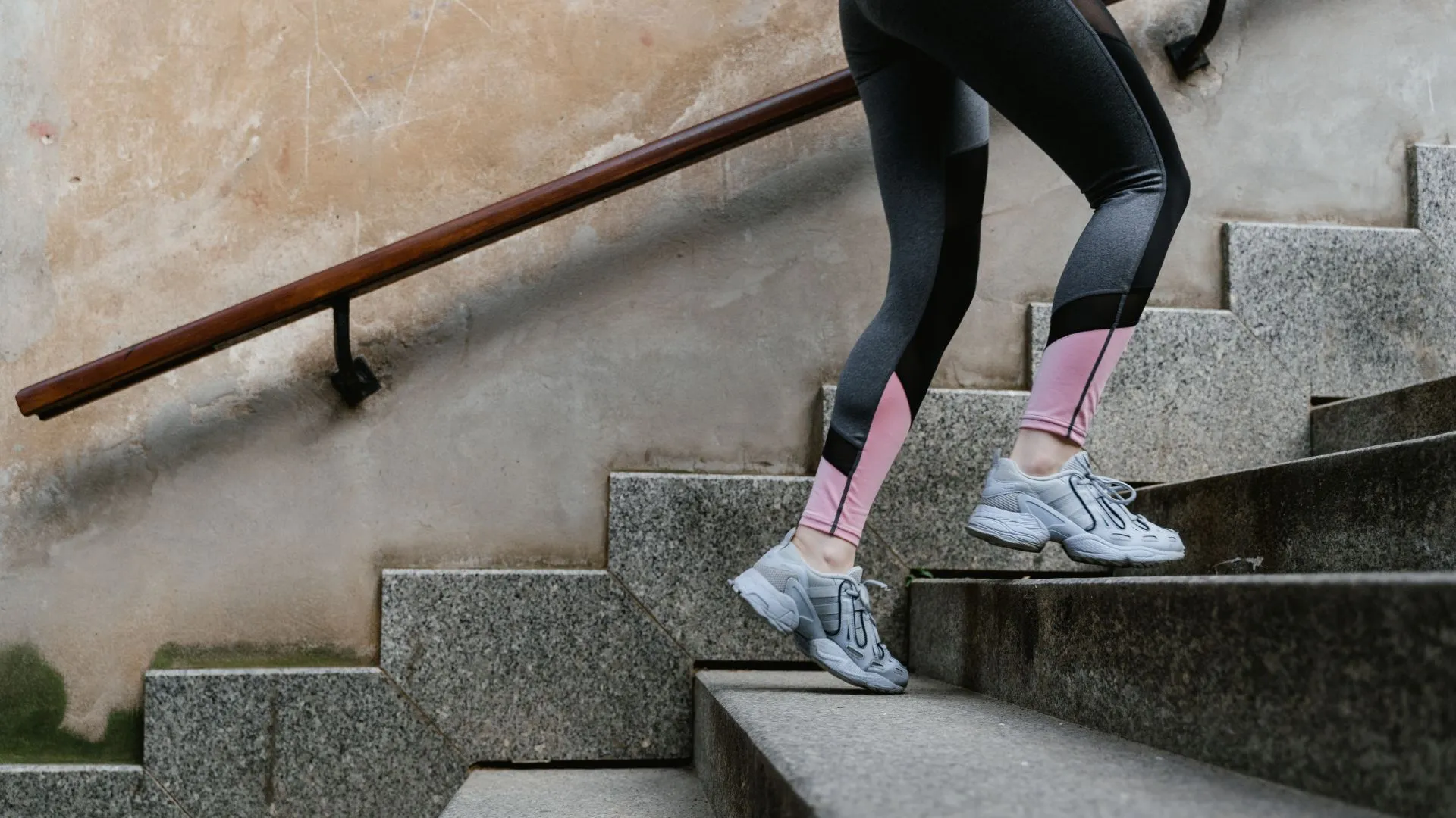 Person in athletic leggings and sneakers climbing outdoor stone stairs during a workout