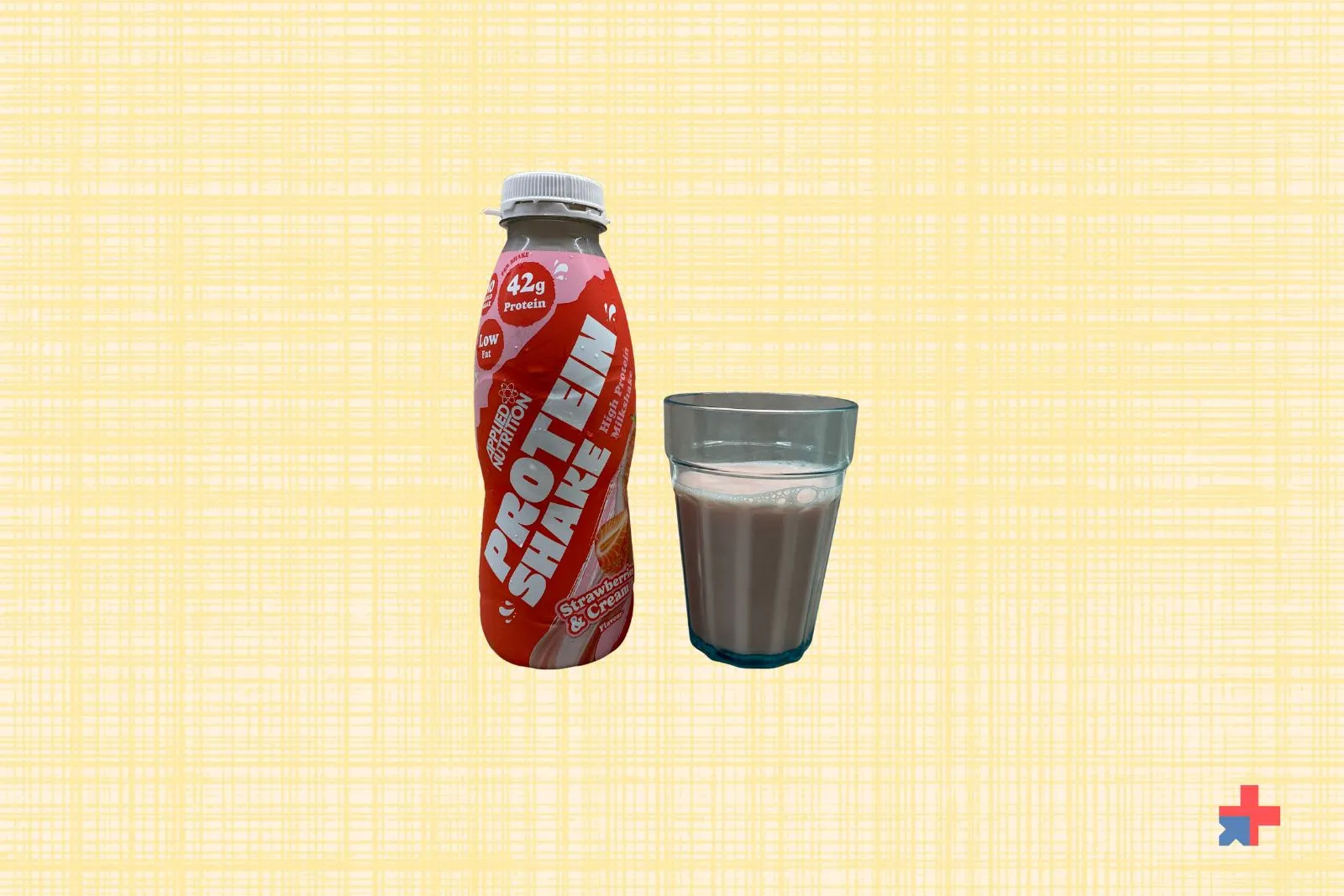 Applied Nutrition Strawberry & Cream High Protein Shake bottle standing beside a glass of the poured shake.